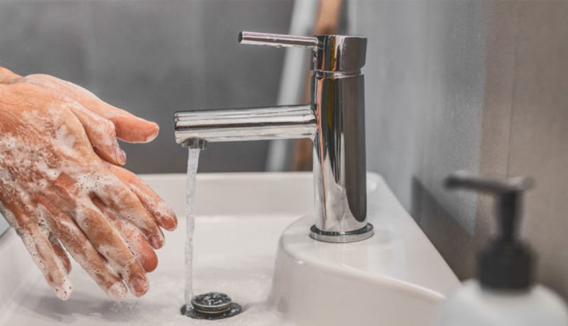 Man washing hands to prevent spreading COVID-19.