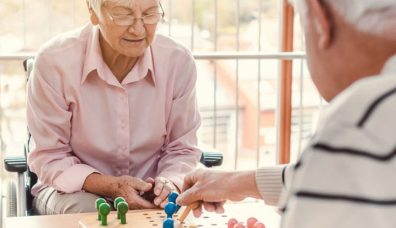Elderly white couple at memory care facility playing chess