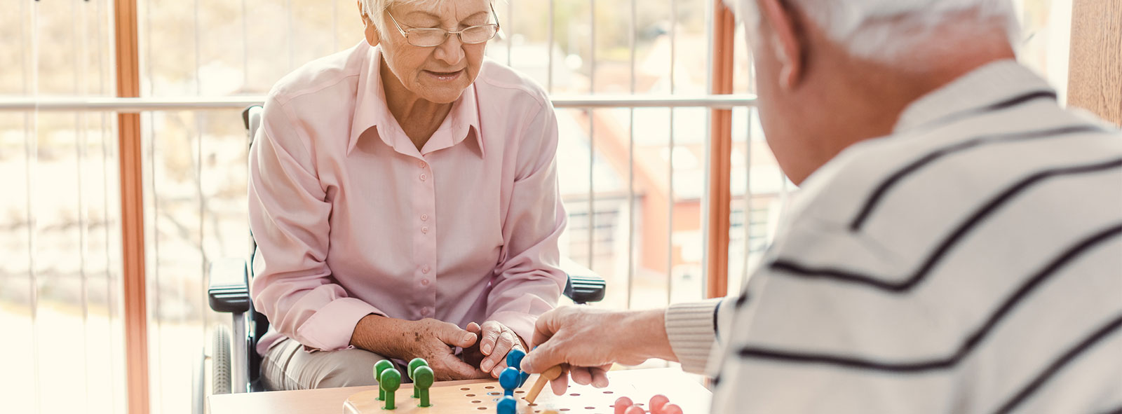 Elderly white couple at memory care facility playing chess