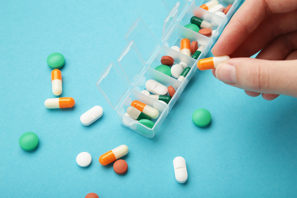 Close up of Hand Sorting Pills in Pillbox