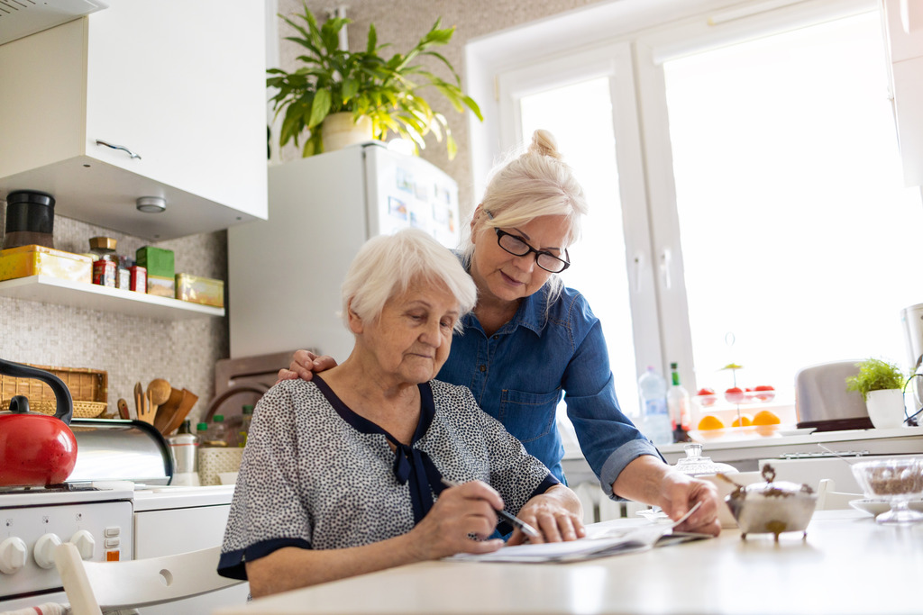 Woman Assisting her Elderly Loved One Fill out Paperwork Advance Care Planning for a Chronic Condition