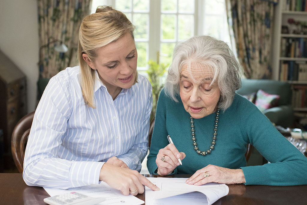 A Daughter Helping Her Senior Mother Fill Out Paperwork Purpose Of A Healthcare Power Of Attorney