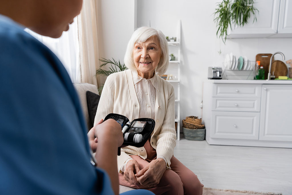 A Nurse Caregiver Sitting Beside A Senior Woman On A Couch While Holding A Diabetes Care Kit Diabetes In Assisted Living