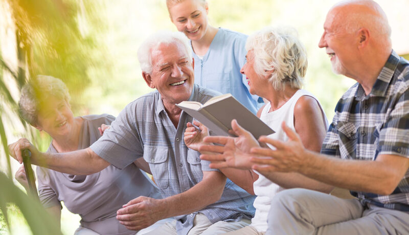 A Group Of Senior Adults Laughing While Looking Through A Book Together Social Isolation In Seniors